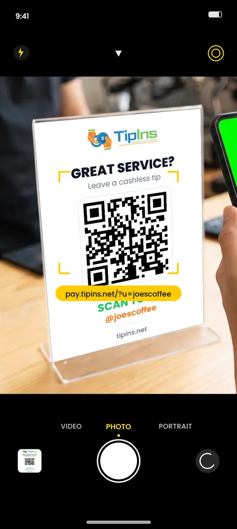 A phone camera pointed at a QR code tip sign